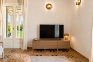 A room with a flat-screen TV on a wooden cabinet, a lamp, and a patterned rug. - Villa Ulìa SicilyMyHome (Ispica)