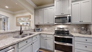 A kitchen with white cabinets, a stainless steel range, a microwave, and a toaster.