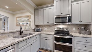 A kitchen with white cabinets, a stainless steel range, a microwave, and a toaster.
