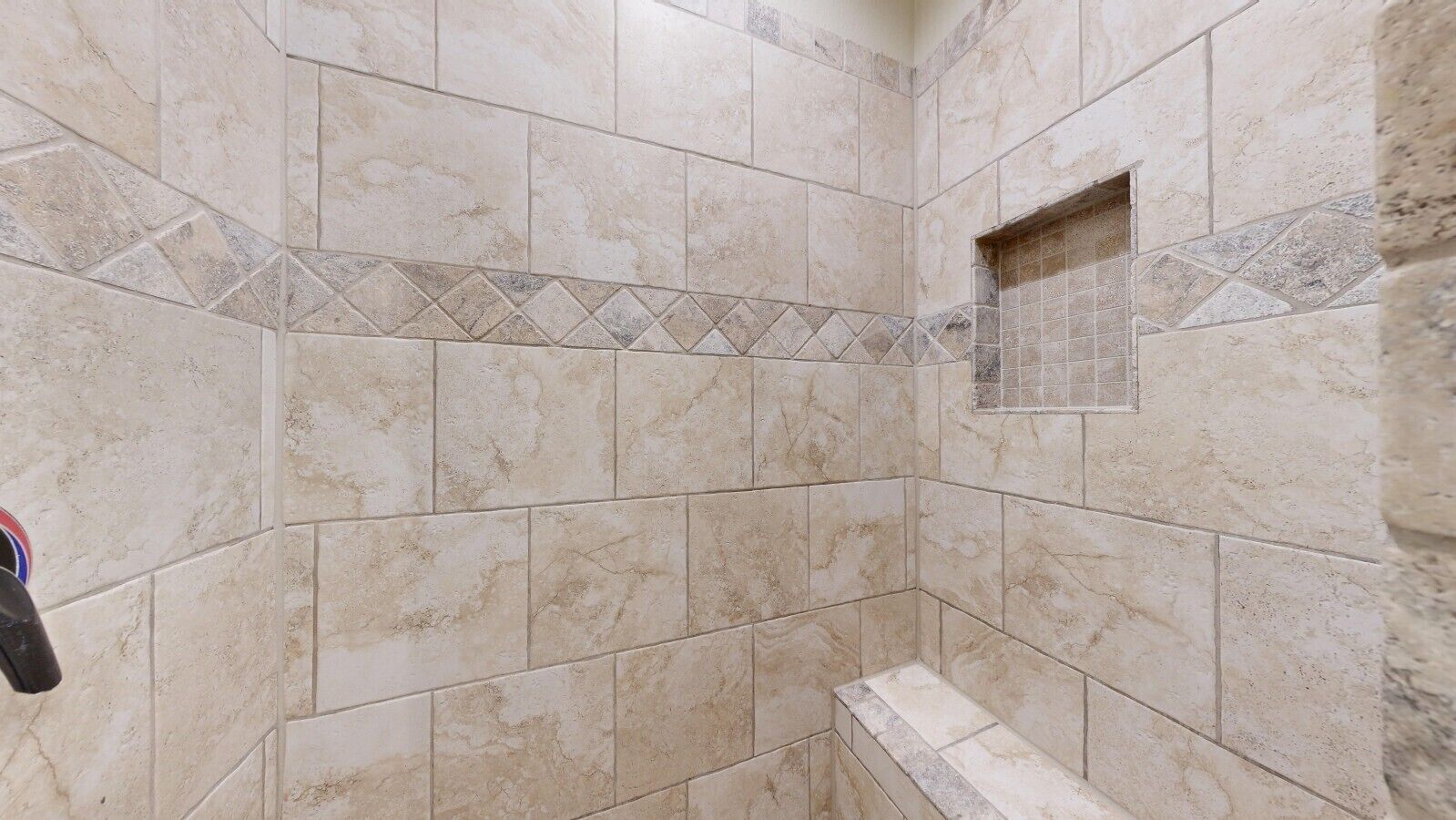 A tiled shower area with a rectangular shower stall and a small window.