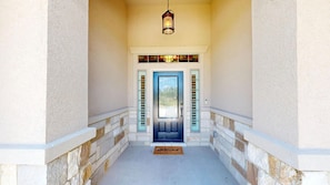 A covered porch with a door, a lantern, and a doormat.