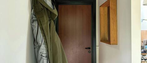 A hallway with a coat rack, a wooden door, and a small wooden table with shoes.