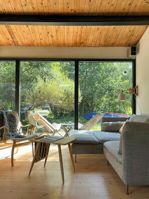 A modern interior with a large window, wooden ceiling, and a sofa. - Idyll on natural plot near beach in Odsherred (Vig)