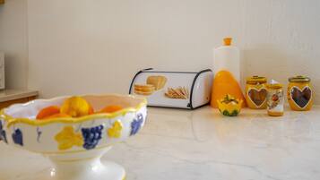 Una encimera de cocina con un bol de fruta, un tostador y dos frascos con tapas decorativas.