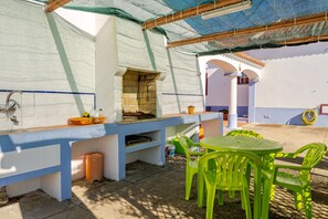 An outdoor kitchen area with a grill, a sink, and a table with chairs. - Cottage 'Casa Dos Girassóis' with Shared Pool, Wi-Fi and Air Conditioning (Évora)