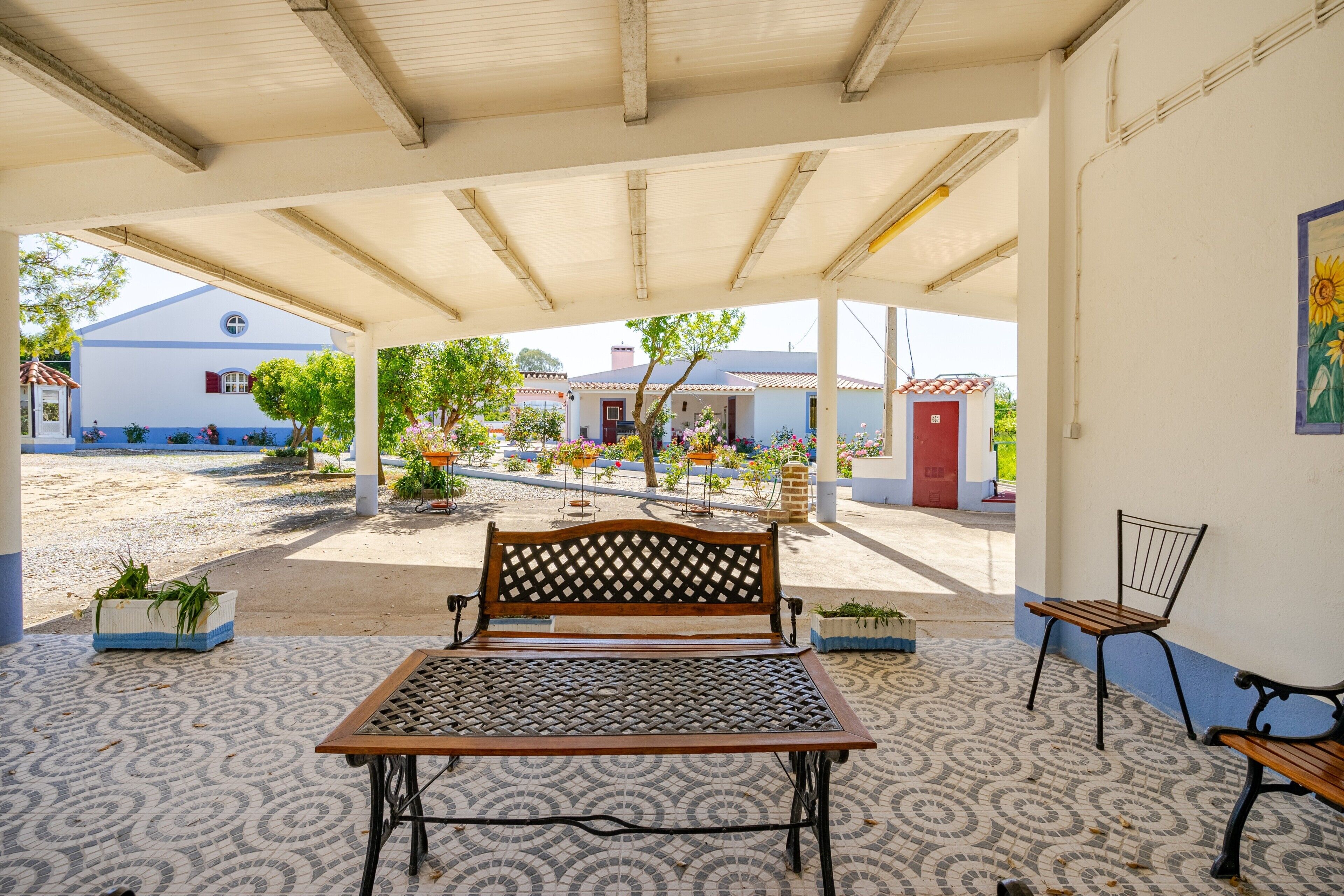 An outdoor seating area with a bench, a table, and chairs.