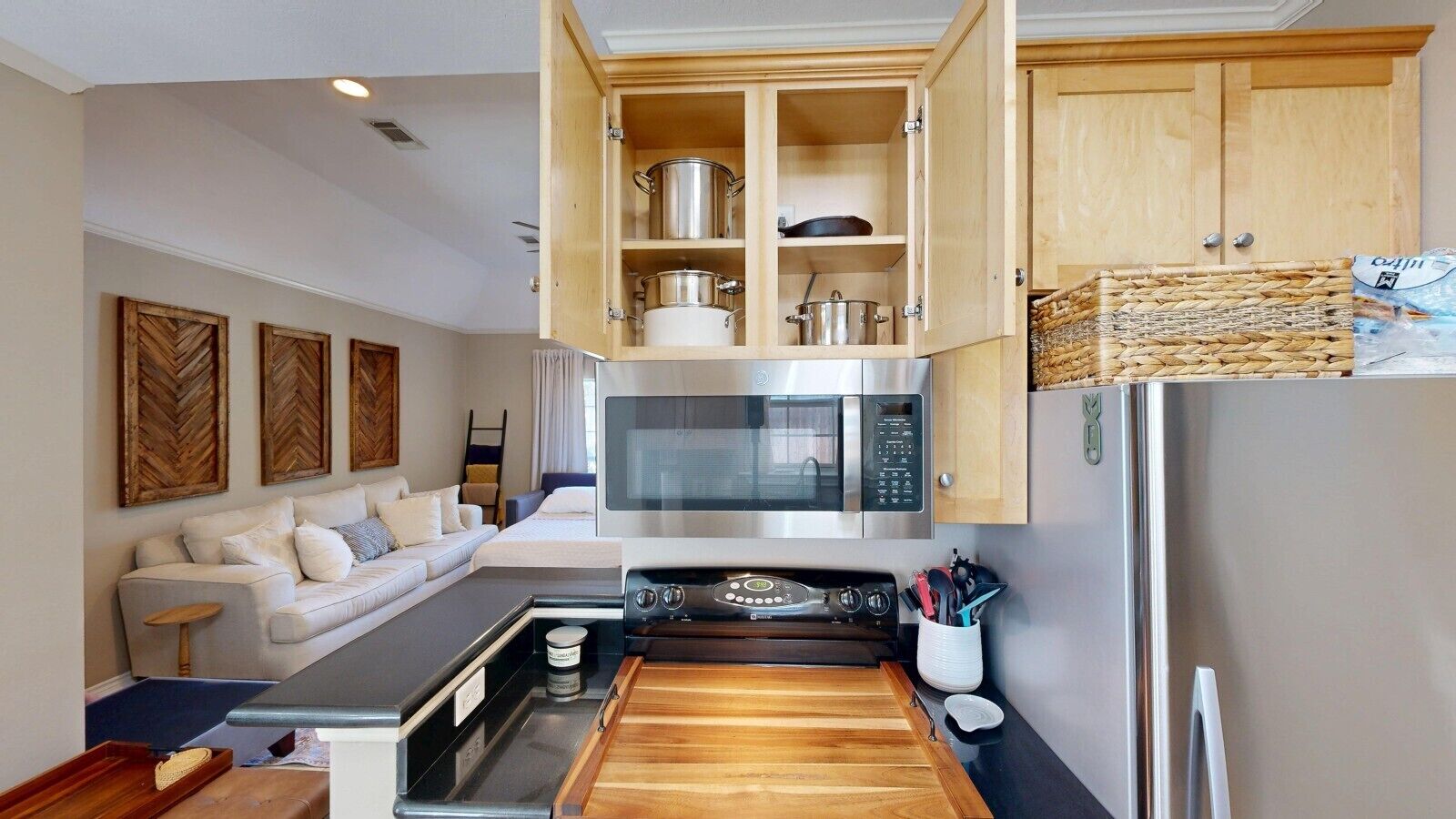 A compact kitchen with a microwave, stove, and wooden cabinets.