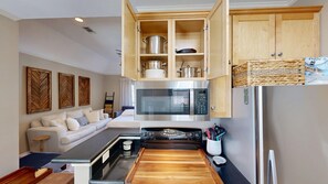 Una cocina compacta con microondas, estufa y armarios de madera.