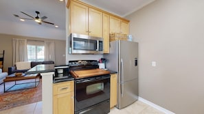 A modern kitchen with a stove, microwave, and refrigerator. There is a dining area with a sofa and a coffee table. - Legends Landing - Under 3 miles from TAMU! (Bryan)