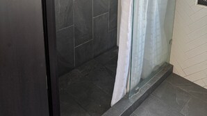 Una zona de ducha con azulejos oscuros y puerta de cristal.