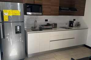 Een moderne keuken met roestvrijstalen apparatuur, een magnetron en een koffiezetapparaat.