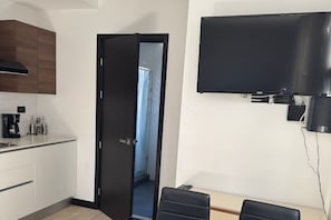 A modern kitchen with white cabinets, a black countertop, a coffee maker, and a flat-screen TV mounted on the wall. - EON Zone 10 | Luxury, Views, and Comfort—All in One Apartment (Ciudad de Guatemala)