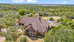 A large brick house with a swimming pool and a basketball court. - The Canyon Social - Pool - Hot Tub - Sport Court (Dripping Springs)