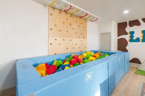 A room with a climbing wall, a foam pit, and a wall with abstract art. - The Canyon Social - Pool - Hot Tub - Sport Court (Dripping Springs)