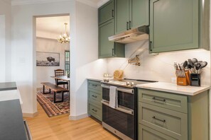 A kitchen with green cabinets, a built-in oven, and a countertop with kitchen utensils. - The Canyon Social - Pool - Hot Tub - Sport Court (Dripping Springs)