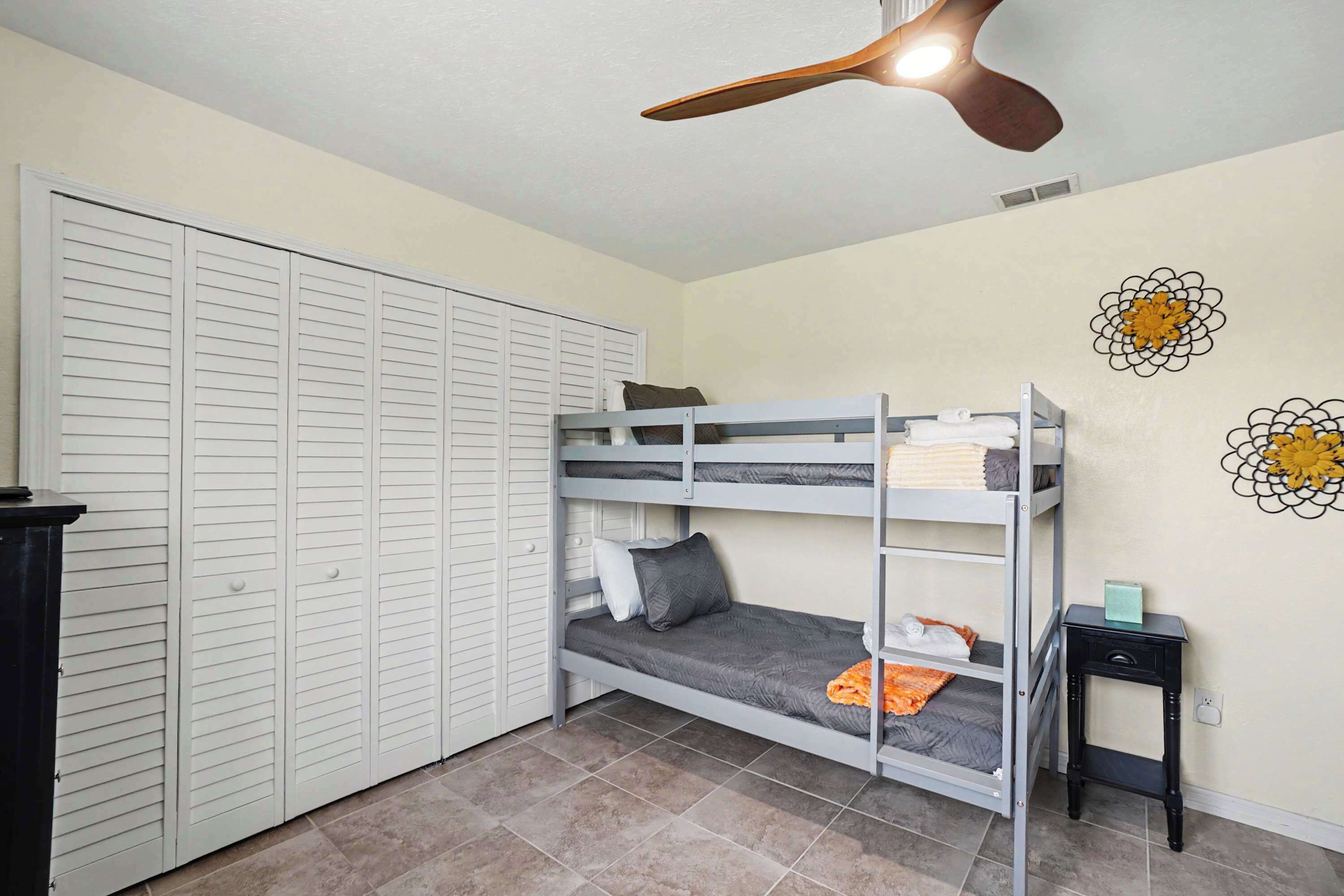 A room with a bunk bed, a wardrobe, and a ceiling fan.