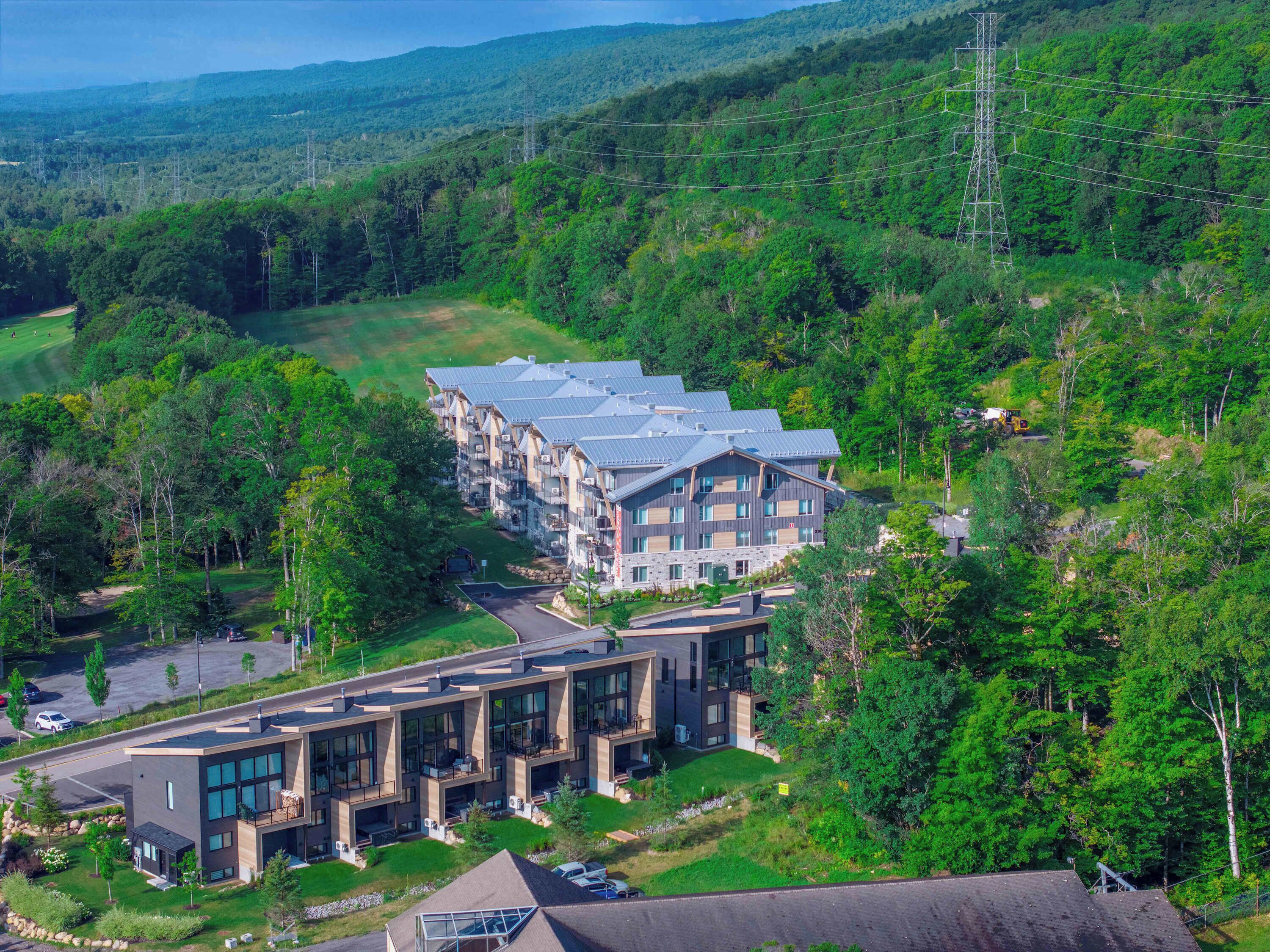 A modern hotel with multiple floors, large windows, and a parking area.