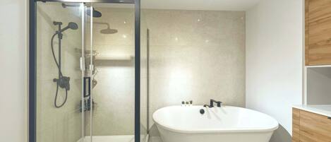 A modern bathroom with a glass-enclosed shower, a freestanding bathtub, and wooden cabinetry.