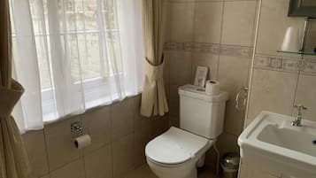 Un bagno con WC, lavandino e finestra con tende.