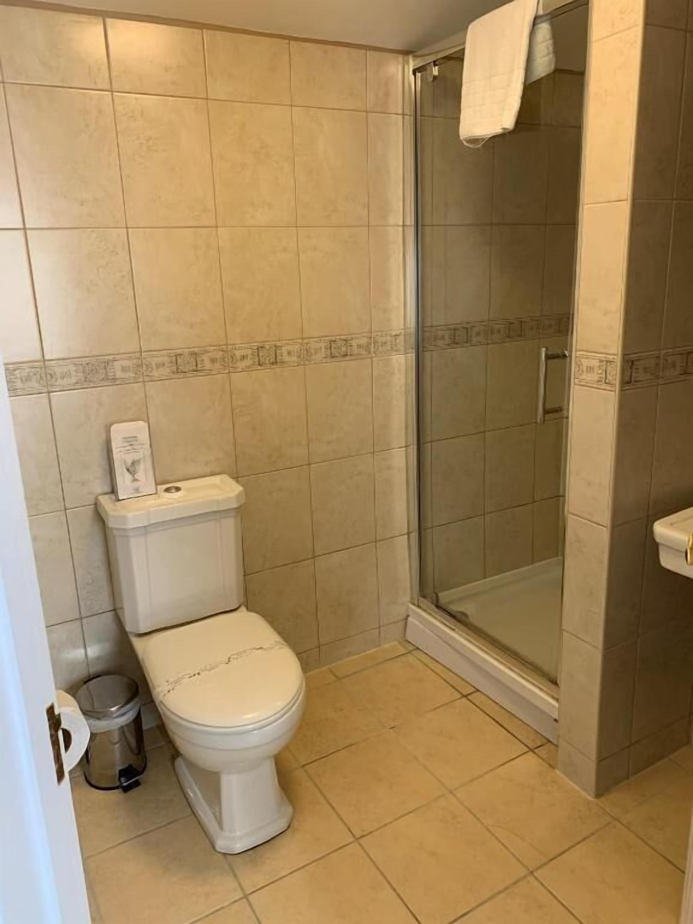 Un bagno con un WC, un cestino e una zona doccia.