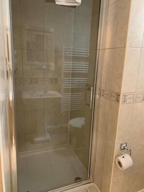 A glass-enclosed shower stall with a toilet and towel rack visible.
