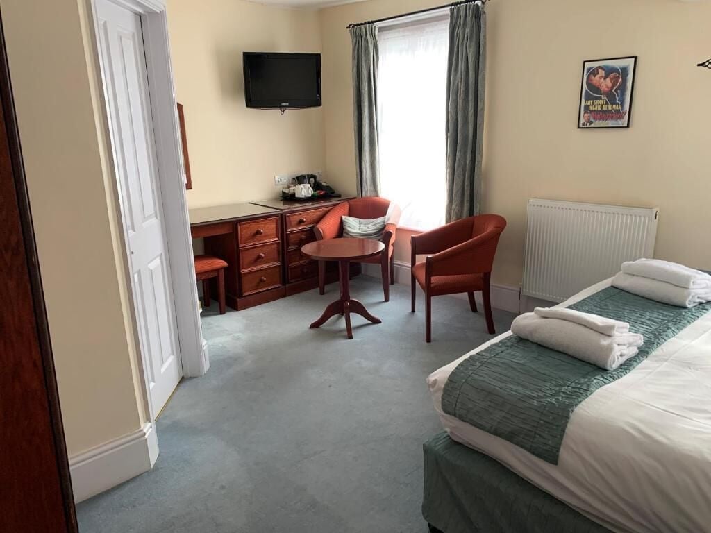 A hotel room with a bed, a desk, a chair, a television, and a window with curtains.