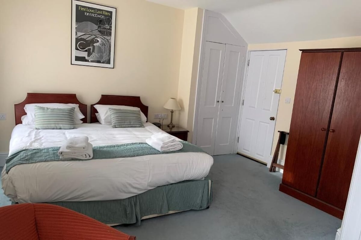 Een hotelkamer met een bed, een stoel, een kledingkast en een poster aan de muur.