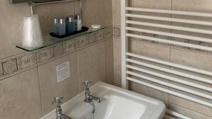 A bathroom with a white sink, a mirror, and a towel rack. - Peregrine House  (Canterbury)