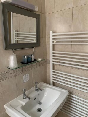 Een badkamer met een witte wastafel, een spiegel en een handdoekrek.