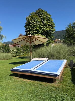 En solstol med ett solskydd i ett grönområde utomhus.