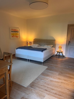 A bedroom with a bed, bedside lamps, a chair, a rug, and a door. - Exclusive lakeside villa on Lake Attersee, featuring a boathouse, a seating area, and a dock (Unterach am Attersee)