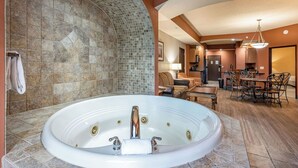 A spacious bathroom with a large bathtub, a shower area, and a seating area with a table and chairs.