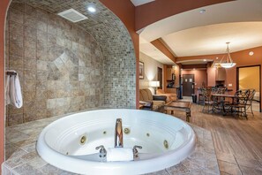 A spacious bathroom with a large bathtub, a shower area, and a seating area with a table and chairs.