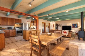 A spacious kitchen with wooden cabinets, a central island, and a dining area with a large table and chairs. - Vistas de Las Animas - Sweeping Fall Foliage Views (Arroyo Seco)