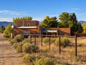 Un bâtiment moderne doté d’un toit plat, entouré d’herbe sèche et d’arbres.
