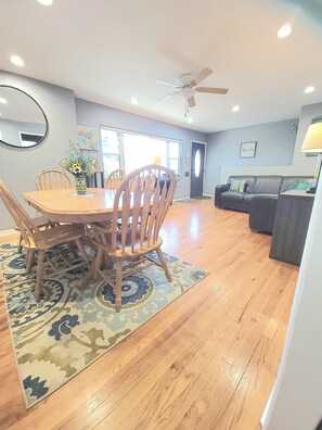 A dining area with a wooden table and chairs, a ceiling fan, and a patterned rug. - Charming 5-bedroom house fits 12 guests in cozy Cheyenne (Cheyenne)