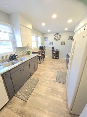 A kitchen with a wooden countertop, dark cabinets, a microwave, and a dining area with a chair and table. - Charming 5-bedroom house fits 12 guests in cozy Cheyenne (Cheyenne)