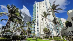 A high-rise hotel with multiple balconies, surrounded by palm trees and a well-maintained lawn. - The Tides Building (Hollywood)