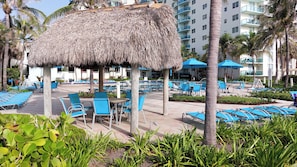 A resort with a pool area, lounge chairs, and a thatched-roof structure. - The Tides Building (Hollywood)