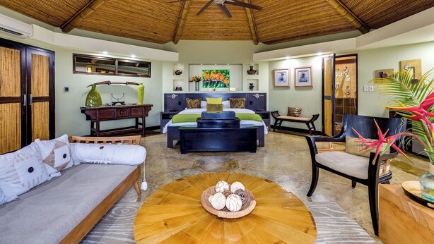A well-lit room with a bed, a sofa, a coffee table, and a ceiling fan. - Villa Voz - 180° Sunset, One Plunge Pool, Zero Interruptions. (Savegre de Aguirre, Puntarenas Province)