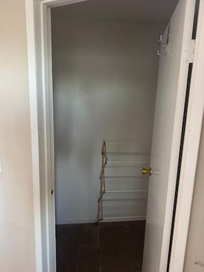 Un pasillo estrecho con una puerta a la derecha y un perchero a la izquierda.