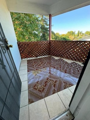 Un balcón con piso estampado, un cerramiento de celosía y vistas a la vegetación.