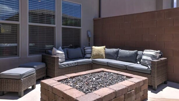 A patio area with a sectional sofa, two side tables, and a fire pit.