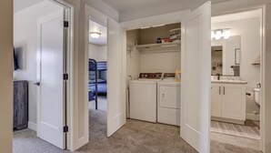 A laundry room with a washing machine, dryer, and a shelf with laundry supplies.