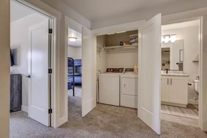 A laundry room with a washing machine, dryer, and a shelf with laundry supplies.