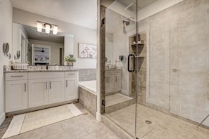 A modern bathroom with a glass-enclosed shower, white cabinetry, and a large mirror.