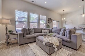 A modern living room with a sectional sofa, a coffee table, and a lamp.