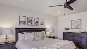 A bedroom with a bed, nightstands, a dresser, and a ceiling fan.