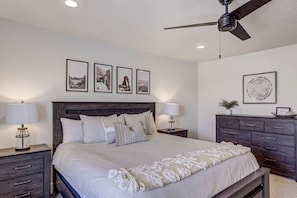 A bedroom with a bed, nightstands, a dresser, and a ceiling fan.