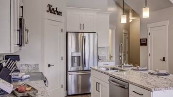 A modern kitchen with white cabinetry, stainless steel appliances, and granite countertops.